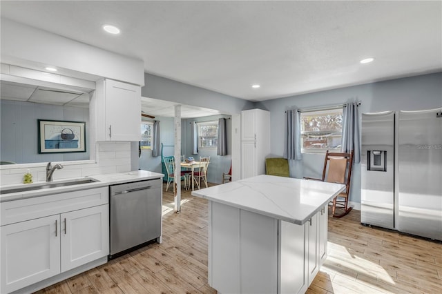 kitchen with stainless steel appliances, sink, white cabinets, and light hardwood / wood-style floors