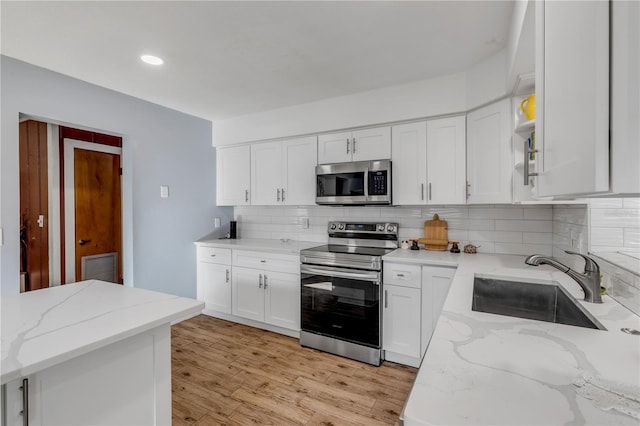 kitchen featuring white cabinetry, sink, light stone countertops, and appliances with stainless steel finishes