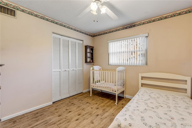 bedroom with ceiling fan, wood-type flooring, and a closet