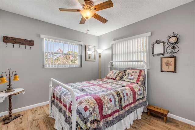 bedroom featuring ceiling fan, a textured ceiling, and light wood-type flooring