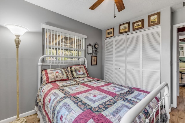 bedroom featuring ceiling fan, hardwood / wood-style flooring, a closet, and a textured ceiling