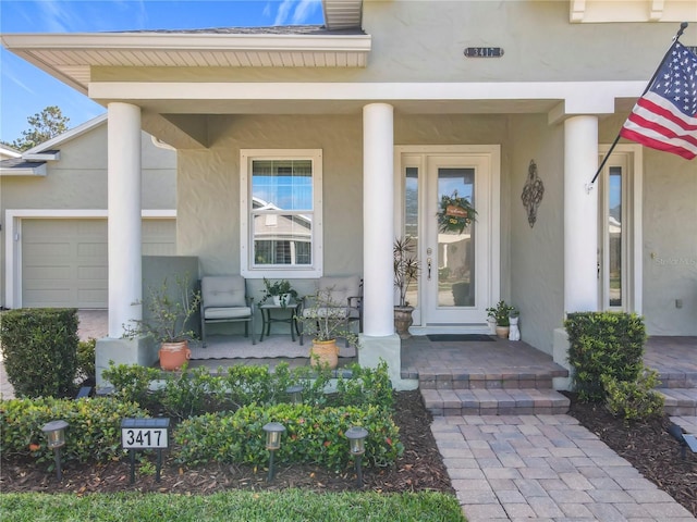 entrance to property featuring stucco siding and covered porch