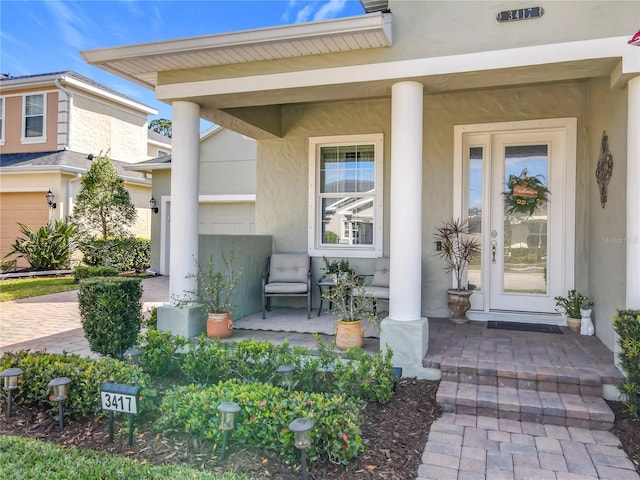 property entrance featuring covered porch, decorative driveway, and stucco siding