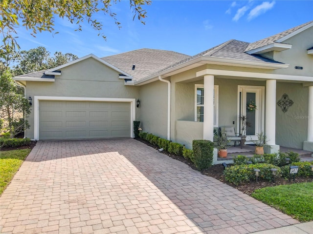 ranch-style house with decorative driveway, a garage, roof with shingles, and stucco siding