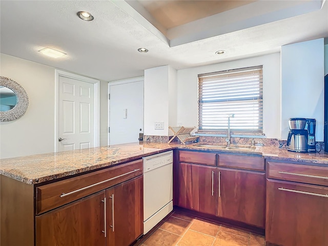 kitchen with sink, light stone counters, white dishwasher, and kitchen peninsula