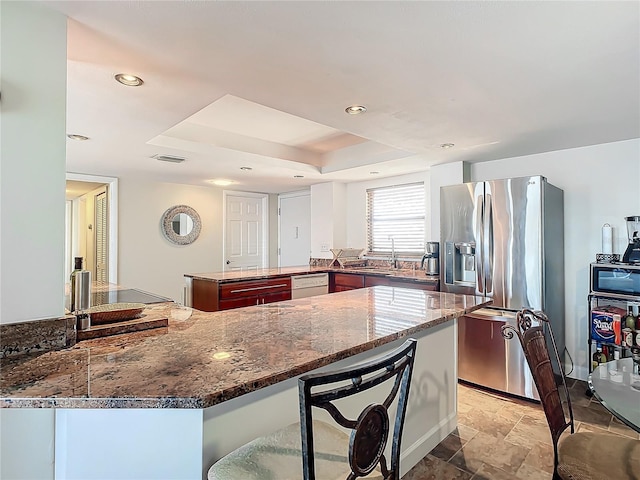 kitchen featuring a breakfast bar, dishwasher, sink, stainless steel fridge, and kitchen peninsula