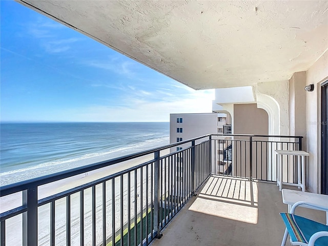 balcony featuring a water view and a view of the beach