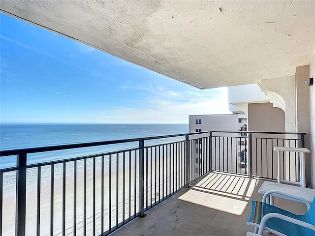 balcony featuring a beach view and a water view