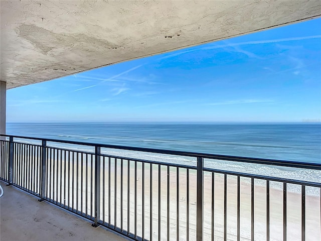 balcony with a water view and a view of the beach