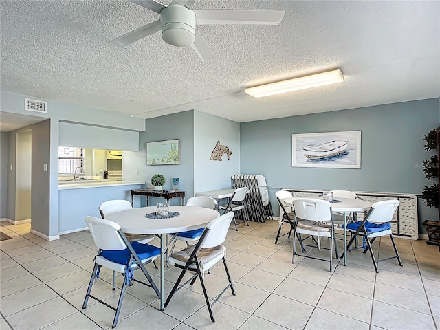 dining area with a textured ceiling, ceiling fan, and light tile patterned flooring