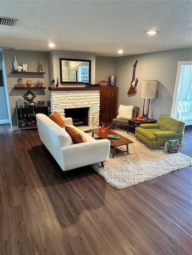 living room with a textured ceiling, dark hardwood / wood-style flooring, and a fireplace