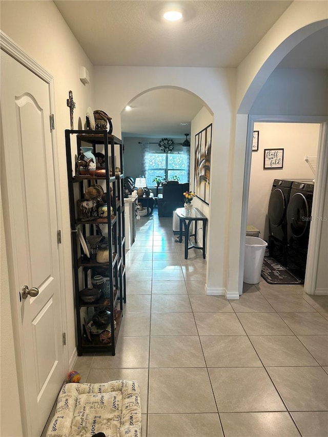 hallway with light tile patterned flooring, washing machine and clothes dryer, and a textured ceiling