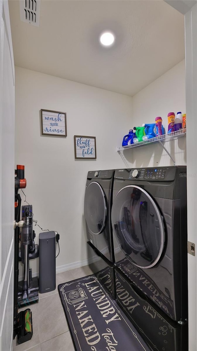 clothes washing area with light tile patterned floors and washer and clothes dryer