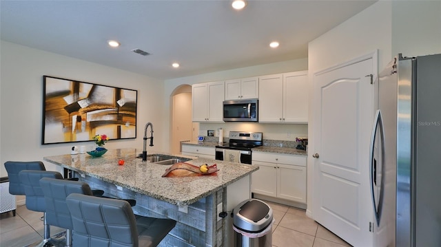 kitchen featuring an island with sink, white cabinets, and appliances with stainless steel finishes