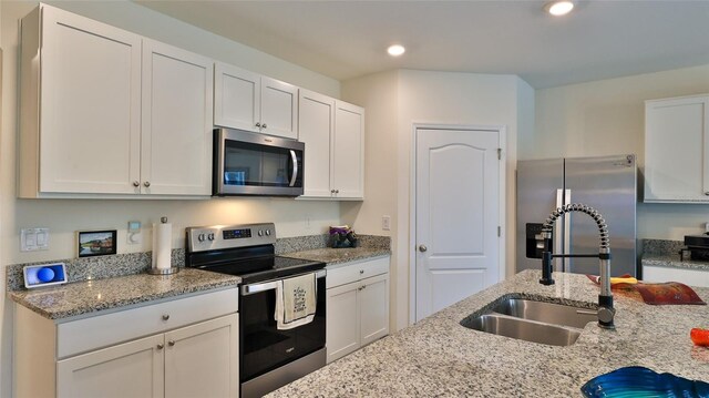 kitchen featuring appliances with stainless steel finishes, light stone countertops, sink, and white cabinets