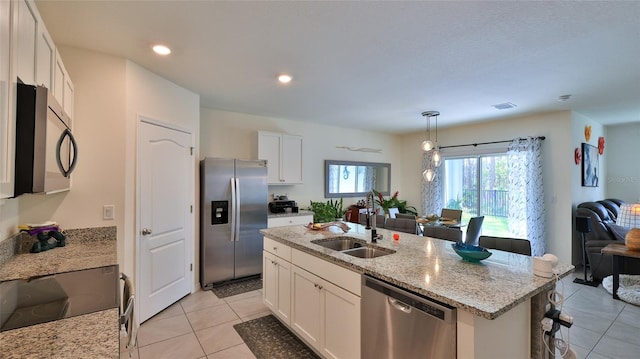 kitchen featuring sink, a kitchen island with sink, white cabinetry, stainless steel appliances, and decorative light fixtures