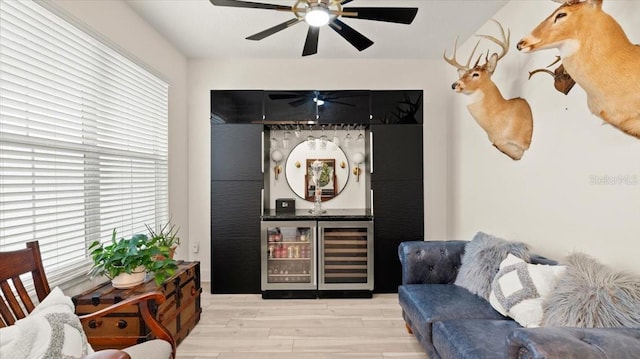 living room with ceiling fan, beverage cooler, and light hardwood / wood-style flooring