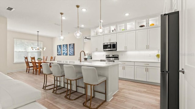 kitchen with sink, white cabinetry, hanging light fixtures, a center island with sink, and stainless steel appliances