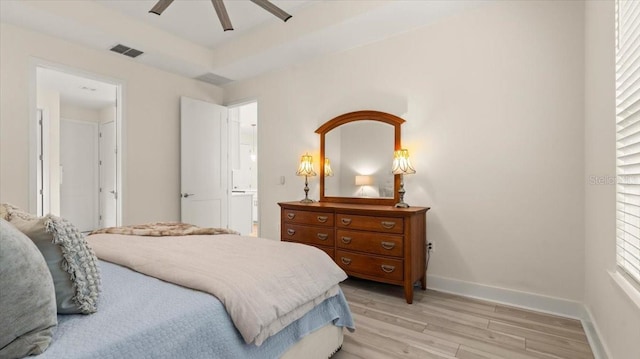 bedroom with a tray ceiling, light hardwood / wood-style flooring, and ceiling fan