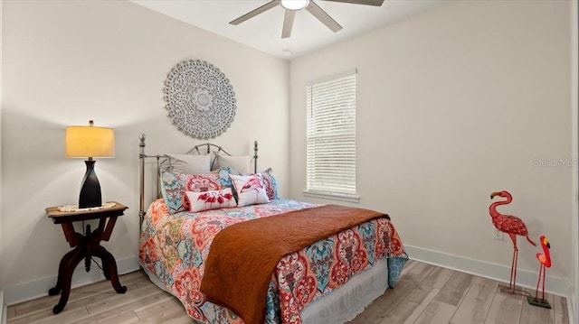 bedroom featuring ceiling fan, light hardwood / wood-style floors, and multiple windows