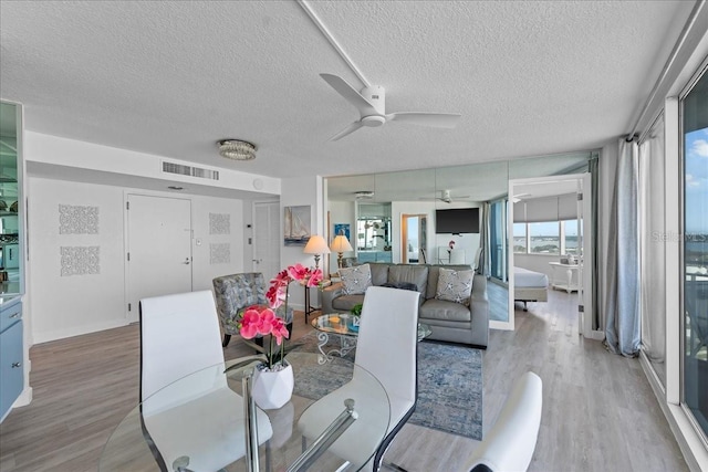 dining room with a textured ceiling, light hardwood / wood-style flooring, and ceiling fan