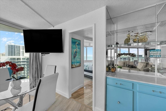 bar featuring blue cabinetry, a textured ceiling, and light wood-type flooring