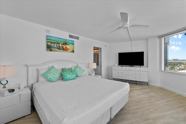 bedroom with ceiling fan, a textured ceiling, and light wood-type flooring