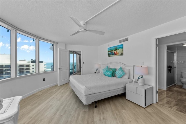 bedroom with ceiling fan, ensuite bathroom, light hardwood / wood-style floors, and a textured ceiling