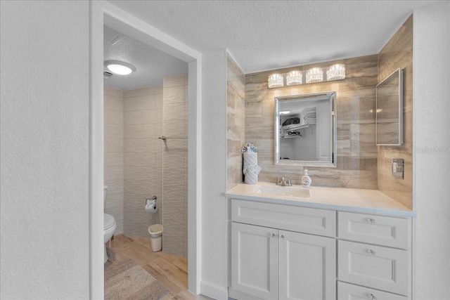 bathroom with wood-type flooring, toilet, a textured ceiling, and vanity