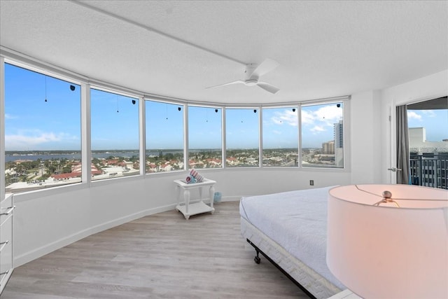 bedroom with ceiling fan, a textured ceiling, and light wood-type flooring