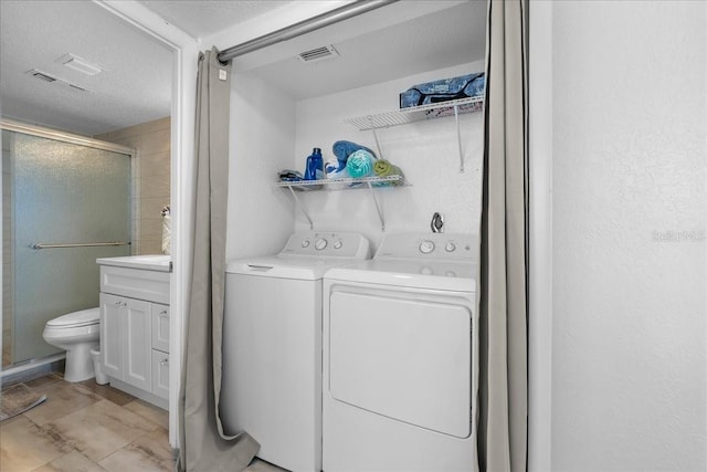 clothes washing area featuring washer and clothes dryer and a textured ceiling