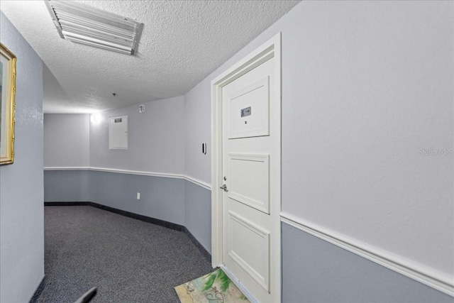 carpeted spare room featuring electric panel and a textured ceiling