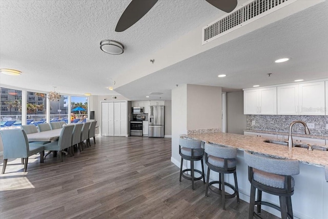 kitchen featuring sink, a breakfast bar area, appliances with stainless steel finishes, tasteful backsplash, and white cabinets