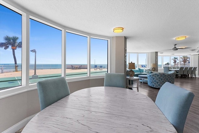 dining space with dark wood-type flooring, a textured ceiling, and a water view