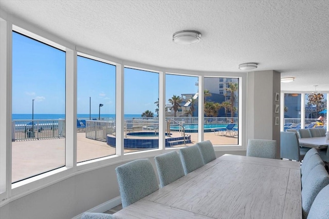 dining area featuring a water view and a textured ceiling