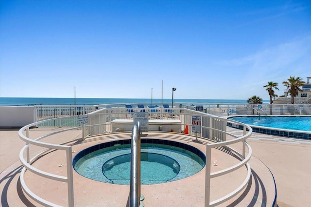 view of swimming pool with a water view and a hot tub