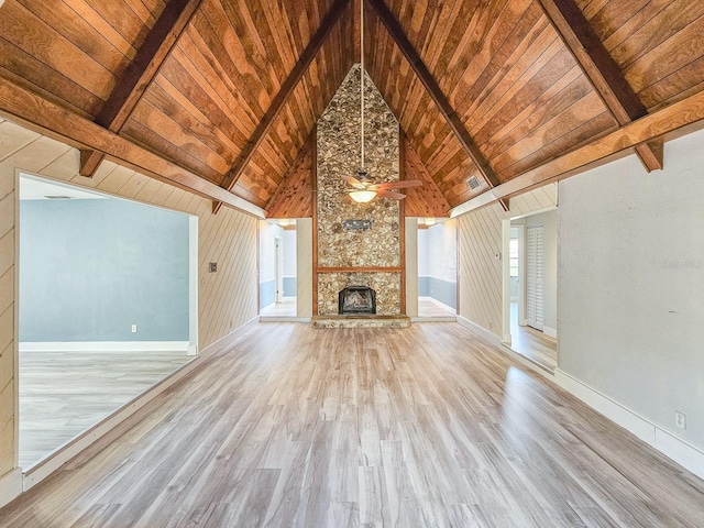 unfurnished living room with beam ceiling, wood ceiling, a fireplace, and light wood-type flooring