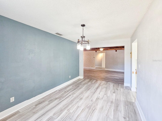 unfurnished dining area featuring a barn door, a textured ceiling, and light hardwood / wood-style flooring