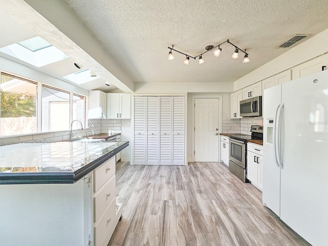 kitchen with white cabinetry, decorative backsplash, appliances with stainless steel finishes, and light hardwood / wood-style flooring