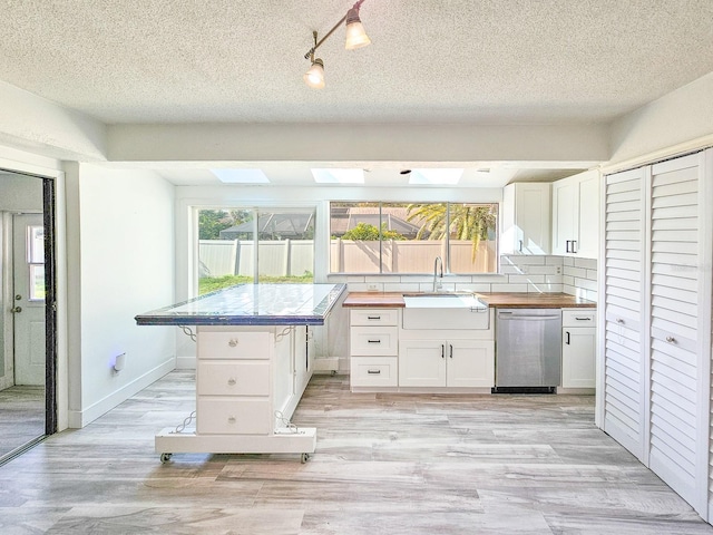 kitchen featuring a healthy amount of sunlight, sink, dishwasher, and white cabinets