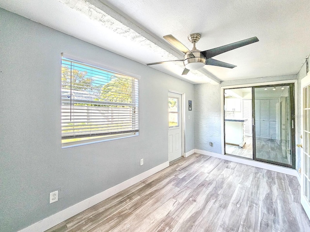 spare room with ceiling fan, a textured ceiling, and light hardwood / wood-style flooring