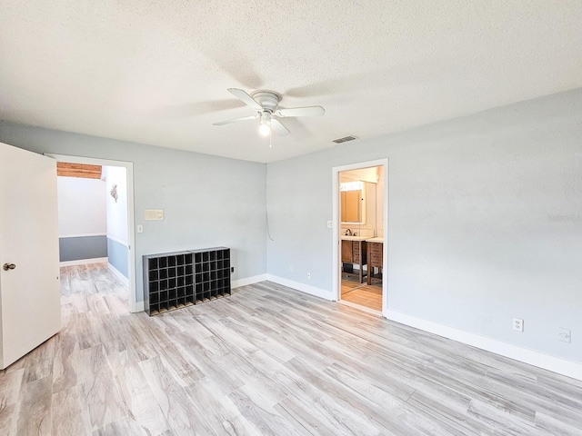 unfurnished living room featuring ceiling fan, a textured ceiling, and light wood-type flooring