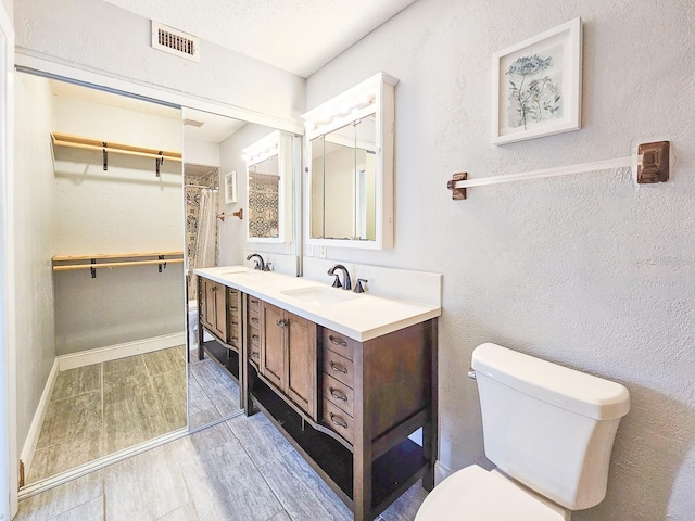 bathroom with vanity, walk in shower, a textured ceiling, and toilet