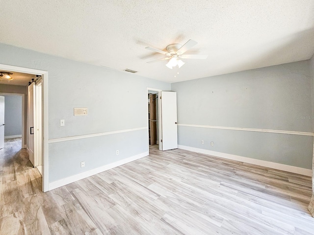 empty room featuring ceiling fan, light hardwood / wood-style flooring, and a textured ceiling