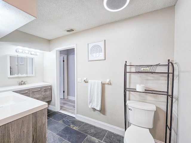 bathroom with vanity, a textured ceiling, and toilet