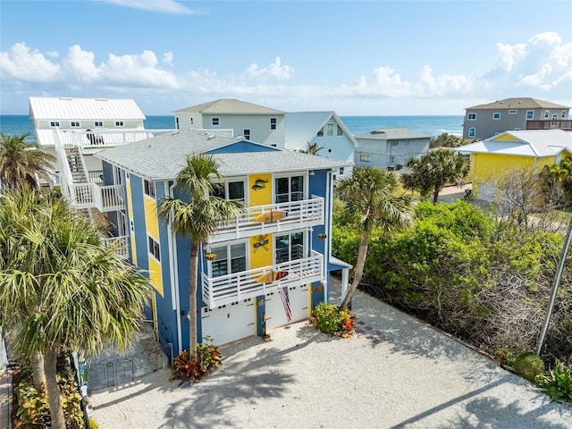 coastal inspired home with a garage, a balcony, and a water view