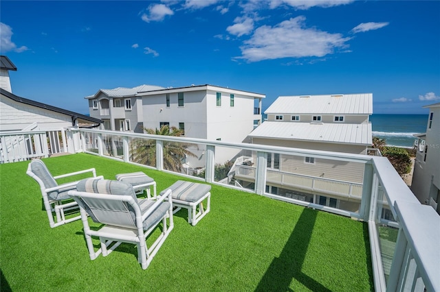 back of house with a balcony, a water view, and a lawn