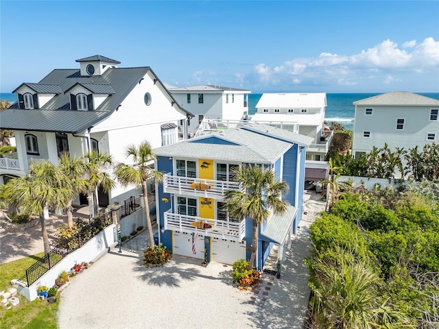 raised beach house featuring a garage, a balcony, and a water view