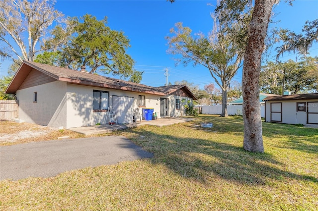 rear view of property with an outbuilding, a patio area, and a lawn