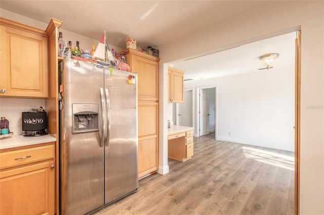 kitchen with light brown cabinetry, stainless steel fridge, and light hardwood / wood-style floors